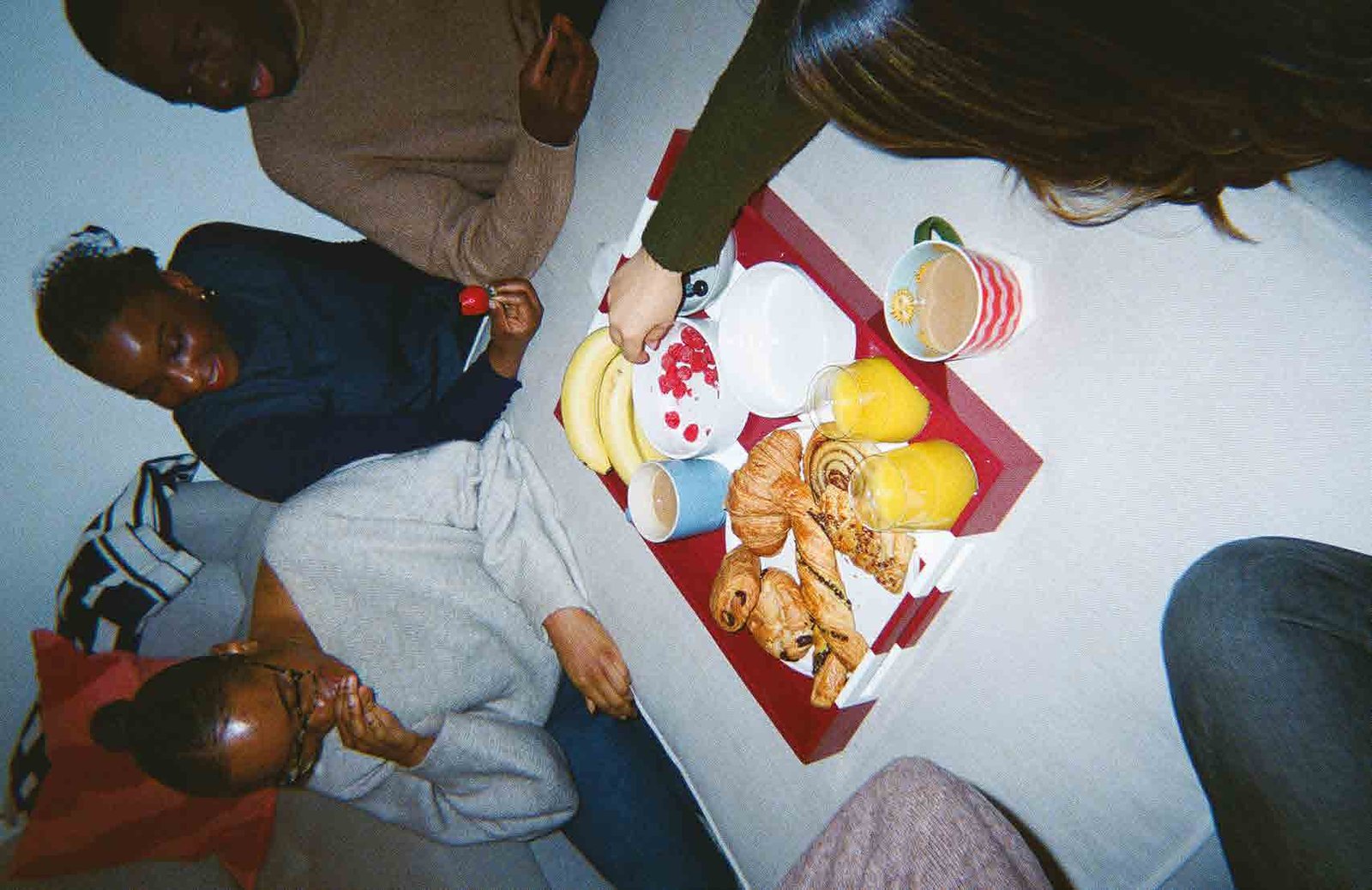 Friends sharing breakfast pastries and coffee around a tray at Alpha