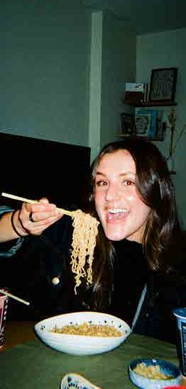 A student laughing while eating noodles at Alpha